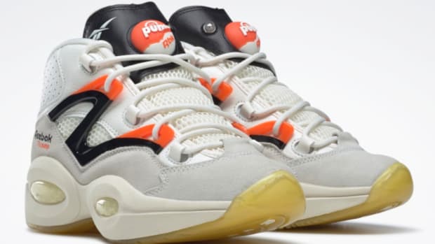 View of white, black, and orange Reebok shoes.